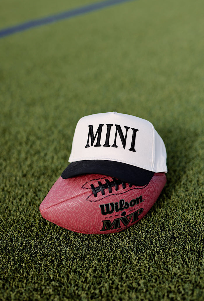 White 'MINI' cap on a pink Wilson MVP football, on artificial grass surface.