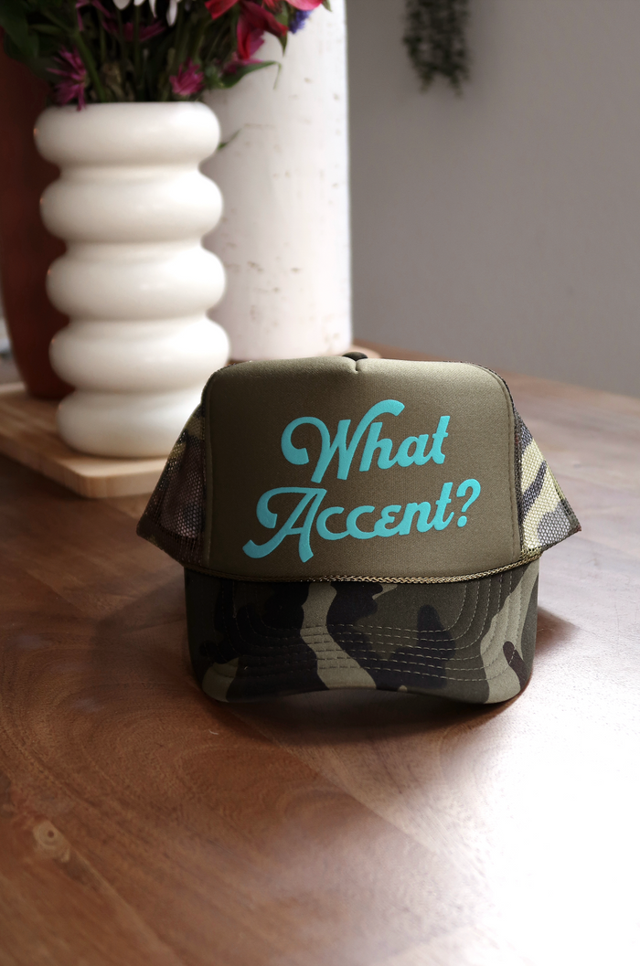 Camo trucker hat with teal 'What Accent?' text, perfect for casual wear and outdoor activities.