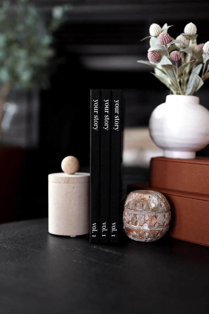 Three black hardcover books titled 'Your Story' on a stylish table with decorative items.