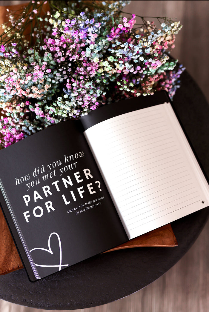 Motivational journal with black cover, featuring prompts about life partners and colorful floral decor.